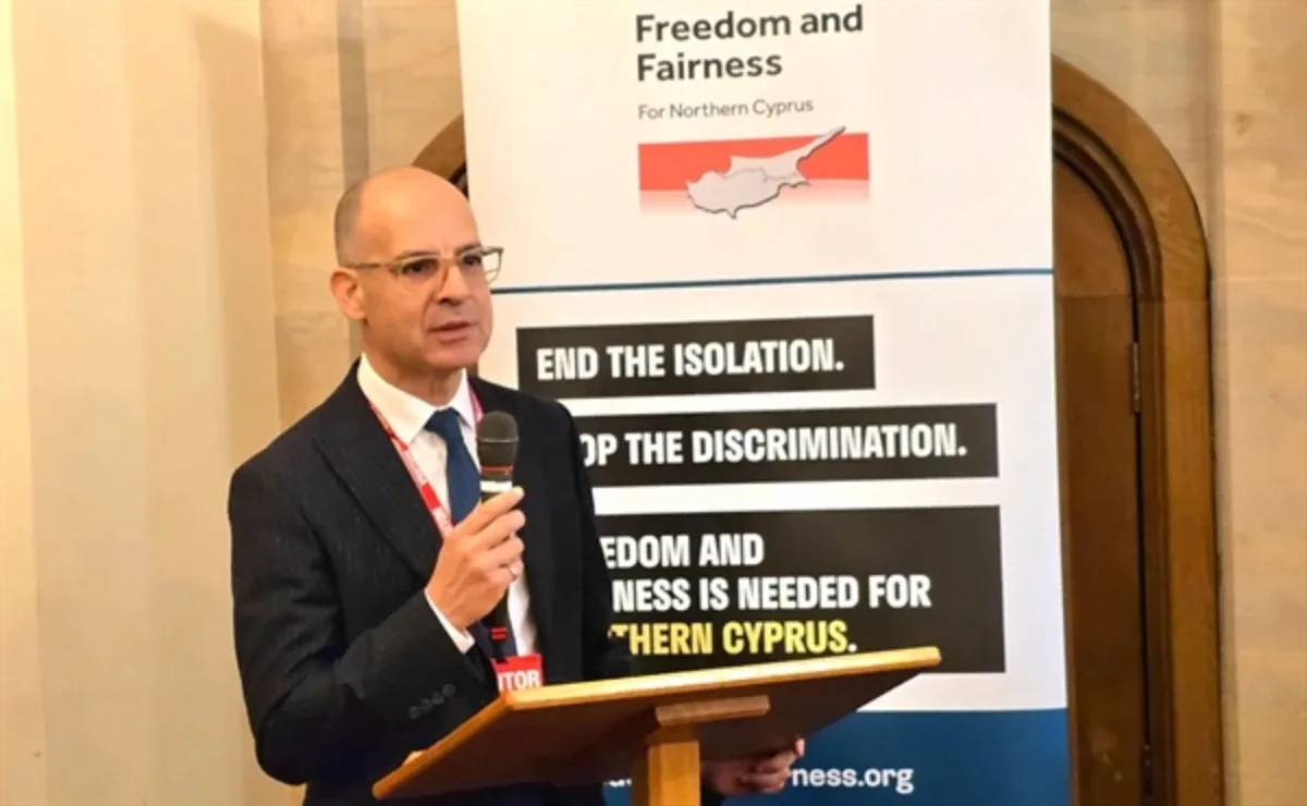 Mehmet Dânâ speaking at a lectern during a UK parliamentary event, with a Freedom and Fairness for Northern Cyprus banner behind him